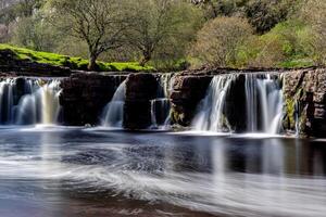 serein cascade avec lisse l'eau couler dans une luxuriant vert paysage dans Yorkshire vallons. photo