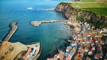 aérien vue de une pittoresque côtier village avec une port, entouré par falaises et le mer dans Staithes, Angleterre. photo