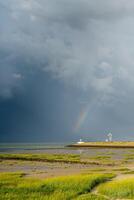 lourd tonnerre des nuages et une arc en ciel plus de le port entrée de le néerlandais ville de terneuzen. photo