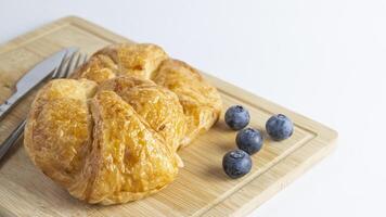 une croissant et une couteau et fourchette sur une Coupe planche photo