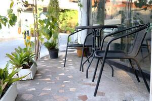 noir Couleur ensemble de métal chaise et table sur béton sol à l'extérieur café boutique, blanc pot et plante décor à côté de, Thaïlande. photo