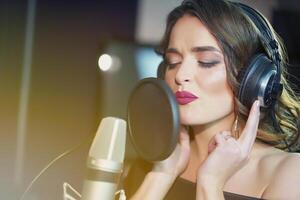 magnifique femme dans écouteurs enregistrements une chanson dans une professionnel enregistrement studio. visage fermer photo