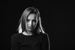 portrait de charmant aux cheveux noirs femme à la recherche devant sur noir Contexte. beauté studio, noir et blanc photo