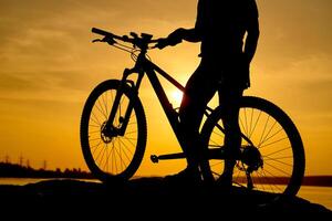 silhouette de une homme sur vélo de montagne, le coucher du soleil photo
