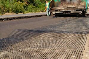 renforcé engrener posé en dehors sur le route par ouvriers dans le processus de construction et réparation travaux de routes photo