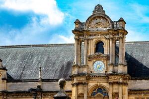 élégant historique bâtiment façade avec fleuri l'horloge la tour en dessous de une clair bleu ciel dans oxford, Angleterre. photo