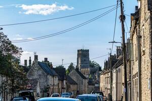 pittoresque européen rue avec historique pierre bâtiments et une église la tour en dessous de une clair bleu ciel. photo