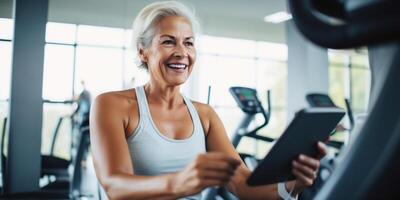 ai généré Sénior femme en utilisant aptitude app dans salle de sport. actif Sénior femme sourit tandis que en utilisant une aptitude application sur sa téléphone intelligent dans une bien équipé salle de sport, représentant santé et La technologie photo