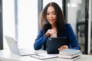 femme d'affaires en cours d'analyse la finance sur tablette et portable à moderne Bureau bureau impôt, rapport, comptabilité, statistiques photo