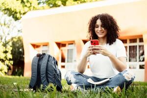 femme étudiant envoyer des SMS sur le intelligent téléphone dans une vert parc. photo