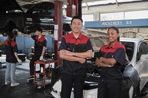 portrait de professionnel mécanicien les partenaires bras franchi et Regardez à caméra, travail à voiture un service garage, content entretien emplois, vérifier et réparation ingénieur Occupation dans automobile industrie entreprise. photo