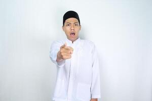 asiatique homme musulman montrer du doigt vers l'avant avec sous le choc expression isolé sur blanc Contexte photo