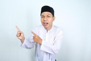 confus asiatique musulman homme montrer du doigt à côté isolé sur blanc Contexte photo