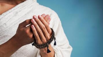 musulman homme portant ihram vêtements est prier avec prière perles dans le sien mains photo