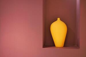 un artefact, une Jaune vase, repose dans une niche sur une rose mur photo