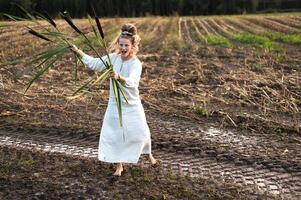 de bonne humeur Jeune femme avec roseaux danses dans coloré fumée dans une champ. photo