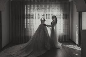 une magnifique la mariée avec une longue voile dans sa chambre, portant une peignoir. mariage robe sur une mannequin. le la mariée dans le Matin avant le mariage cérémonie. photo