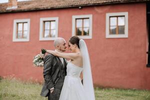 le la mariée et jeune marié embrasser. le la mariée doucement câlins le jeune marié par le épaules. magnifique mariage couple. le concept de romance dans une jeunes mariés relation. voyage de noces. photo