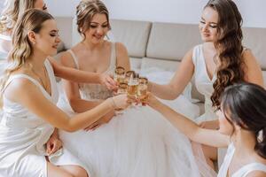photo la mariée avec sa copains en buvant Champagne de lunettes. tondu coup de une magnifique Jeune la mariée et sa demoiselles d'honneur ayant Champagne avant le mariage.