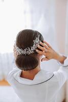 fermer vue de le dos. une diadème dans le de la mariée cheveux. le concept de mariage bijoux. le la mariée est en train de préparer pour le mariage. photo