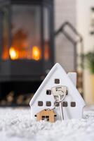 clé de la maison avec porte-clés sur fond de poêle cheminée avec feu et bois de chauffage dans un décor de saint valentin, love home. déménagement dans une nouvelle maison, hypothèque, location et achat immobilier photo