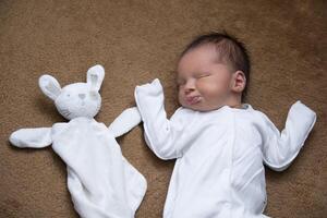 nouveau née bébé avec une doux lapin jouet sur une beige Contexte. photo