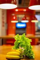 des légumes et des fruits contre le Contexte de une flou cuisine. bananes et salade sur le cuisine tableau. photo