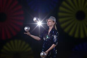 cirque actrice effectue. le fille jongle des balles sur une foncé Contexte dans le projecteurs. photo