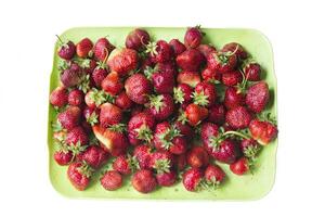 une lot de des fraises dans une assiette Haut vue.rouge baie dans une rectangulaire récipient photo