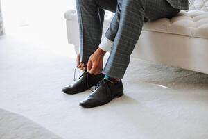 une Jeune homme mettre sur noir cuir bottes à l'intérieur. fermer photo. détail de une jeune marié en mettant sur le sien des chaussures photo