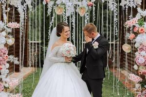 le jeune marié pleure pendant le mariage la cérémonie près le fleur cambre. été mariage dans la nature. elle mentionné Oui. une émouvant moment à le mariage la cérémonie photo