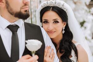 le la mariée et jeune marié embrasser. le la mariée doucement câlins le jeune marié par le épaules. magnifique mariage couple. le concept de romance dans une jeunes mariés relation. voyage de noces. photo