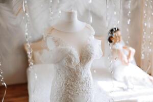 une magnifique la mariée avec une longue voile dans sa chambre, portant une peignoir. mariage robe sur une mannequin. le la mariée dans le Matin avant le mariage cérémonie. photo