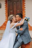 le la mariée et jeune marié embrasser. le la mariée doucement câlins le jeune marié par le épaules. magnifique mariage couple. le concept de romance dans une jeunes mariés relation. voyage de noces. photo