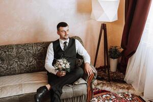 portrait de une Jeune jeune marié à Accueil avant le mariage cérémonie. une Beau homme habillé dans une classique costume. Masculin portrait. photo