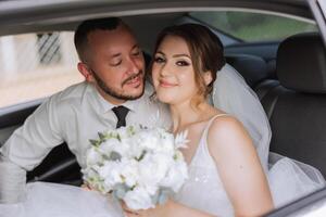 le la mariée regards en dehors de le voiture la fenêtre. fermer portrait de une jolie timide la mariée dans une voiture la fenêtre. le jeune marié baisers le la mariée photo