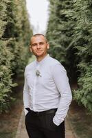 portrait de le jeune marié dans la nature dans le été. élégant grand jeune marié dans un élégant affaires costume. homme d'affaire dans la nature. portrait de une réussi homme. mariage portrait de le jeune marié. photo