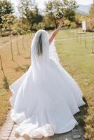 photo de le dos. une magnifique Jeune femme dans une blanc mariage robe est souriant sur une chaud mariage été journée