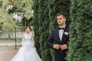 le la mariée est habillé dans un élégant luxuriant blanc mariage robe avec une longue voile et est prêt pour sa jeune marié. le premier réunion de le la mariée et jeune marié photo