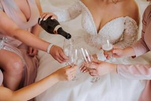 photo la mariée avec sa copains en buvant Champagne de lunettes. tondu coup de une magnifique Jeune la mariée et sa demoiselles d'honneur ayant Champagne avant le mariage.