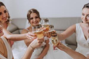 photo la mariée avec sa copains en buvant Champagne de lunettes. tondu coup de une magnifique Jeune la mariée et sa demoiselles d'honneur ayant Champagne avant le mariage.