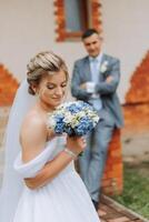 le la mariée est habillé dans un élégant luxuriant blanc mariage robe avec une longue voile et est prêt pour sa jeune marié. le premier réunion de le la mariée et jeune marié photo