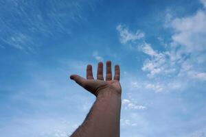 homme main faire des gestes et atteindre le bleu ciel photo