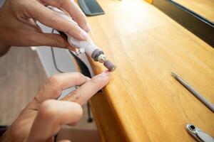 proche en haut photo de une femme enlever le semi-permanent clou polonais de sa ongles avec le papier de verre roue.