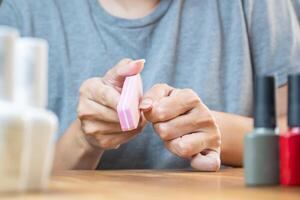 manucure traitement. Jeune femme nettoie sa ongles avec une doux fichier à améliorer apparence. photo