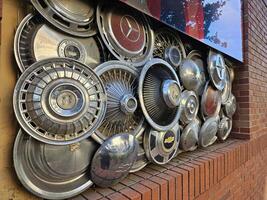 un art pièce attaché à le mur dans centre ville Napa, Californie, fabriqué de ancien voiture roue centre casquettes photo