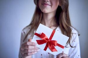 cadeau certificat dans le mains de une adolescent fille portant blanc pyjamas avec rouge cœurs photo