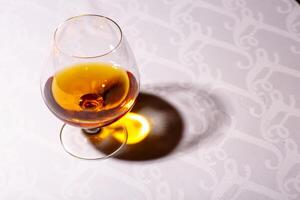 le éblouissement de le verre de français Cognac réfléchi sur blanc languette photo