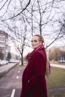 portrait de une élégant âge moyen femme avec tresses sur une printemps rue photo