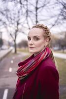 portrait de une élégant âge moyen femme avec tresses sur une printemps rue photo